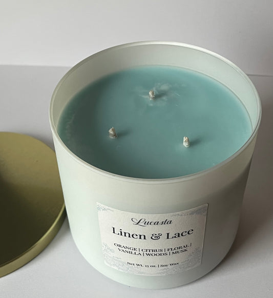 Candle in a white container labeled 'Linen & Lace' with a light blue wax.
