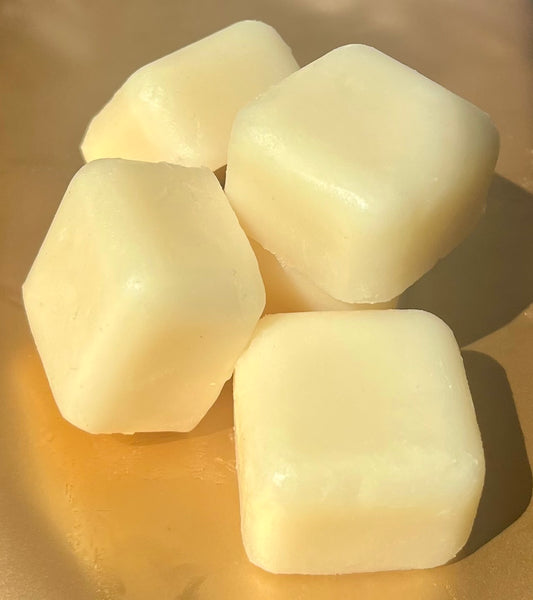 Five Lucasta Silk Melts white massage cubes arranged on a gold background