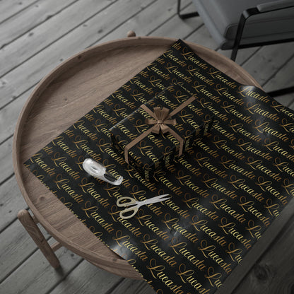 Lucasta black gift wrap with gold text and a bow, styled on a wooden tray