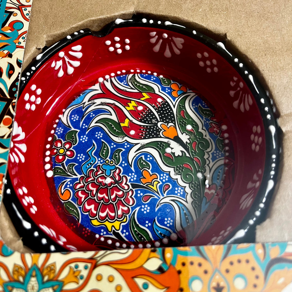 Close-up of red hand-painted Turkish ceramic ashtray with colorful floral pattern