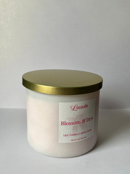 White candle with gold lid and 'Lucasta' label on a white background
