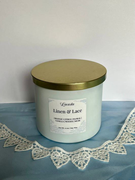 Candle with a gold lid and label on a blue surface with lace trim