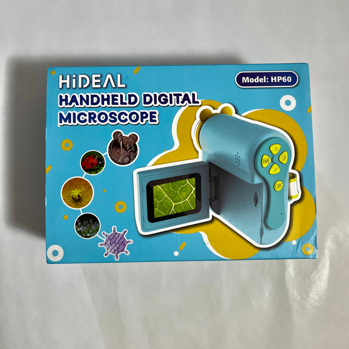 A retail box for a HiDEAL handheld digital microscope, model HP60. The packaging is light blue with yellow graphic accents, featuring an illustration of the light blue microscope and icons of different specimen views.