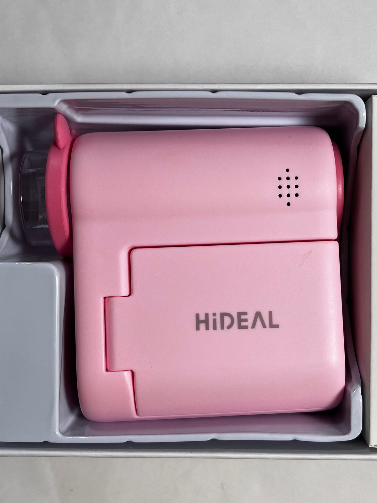 A pink HIDEAL portable microscope displayed inside its white packaging box, set on a light-colored surface.