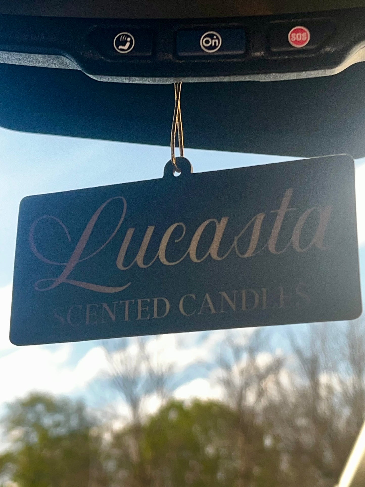 Lucasta Signature air freshener hanging from a car rearview mirror, lifestyle shot