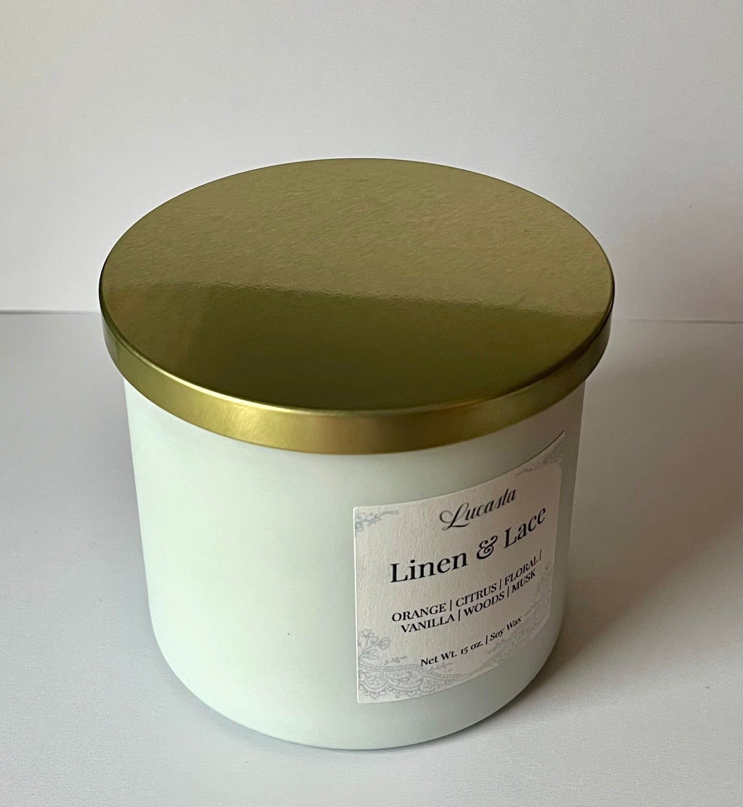 White candle jar with gold lid on a white background