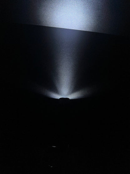 Lucasta Mini Flashlight Keychain in use, casting a spotlight beam in a dark environment