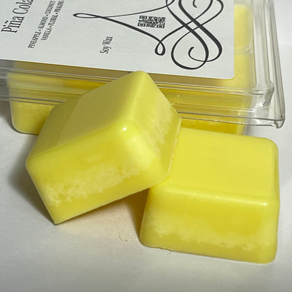 Lucasta Piña Colada soy wax melts in bright yellow, two cubes resting in front of the clamshell packaging on a white background