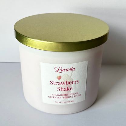 Lucasta Candles Strawberry Shake 15 oz soy candle in a white jar with gold lid, front label view showing scent notes