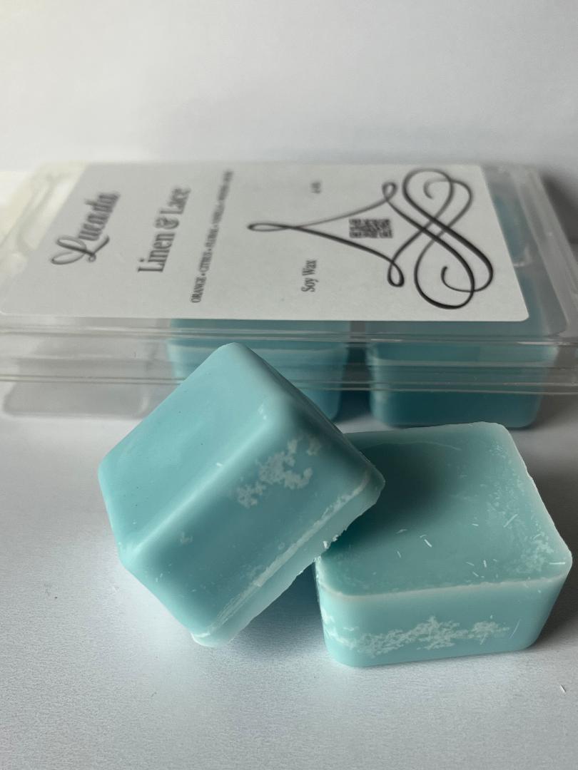 Two Lucasta Linen & Lace light blue wax melts with branded packaging on a white background